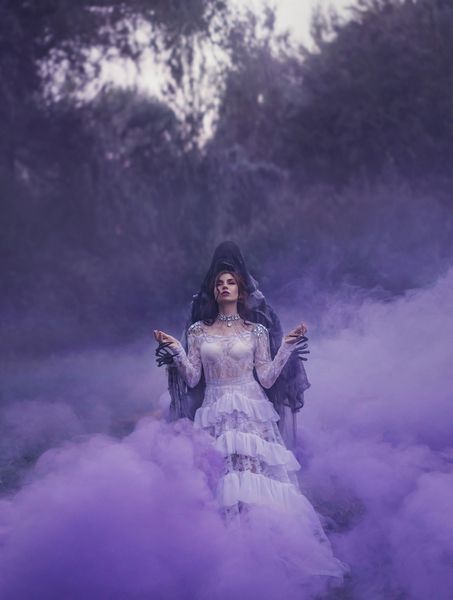 ملکه تاریک با لباس مجلل سفید پرنعمت و گردنبند گرانقیمت نقره ای در آغوش دیو ایستاده در مه مه بنفش با چشمان بسته و نماز می گوید روتوش هنری