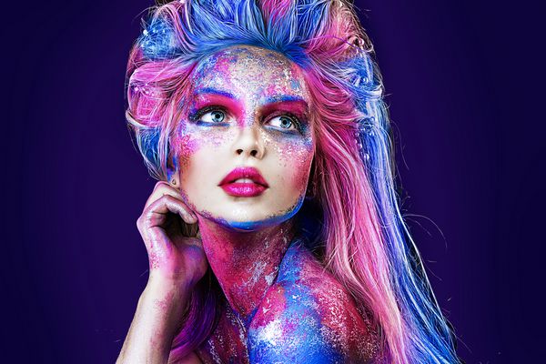نزدیک عکس پرتره از دختر جوان زیبا با نقاشی چهره رنگارنگ آرایش حرفه ای هالووین موهای رنگ پرتره زیبایی موهای آبی و صورتی
