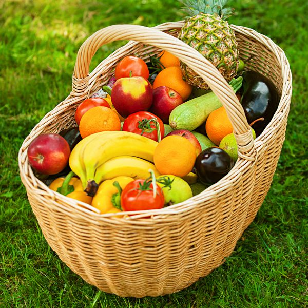 سبد حصیری بزرگ با میوه و سبزیجات روی چمنزارهای سبز است