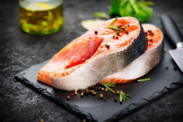 ماهی سالمون استیک ماهی قزل آلا خام ماهی قزل آلا با گیاهان و لیمو و روغن زیتون روی تخته سنگ سرو شد آشپزی سالمون غذای دریایی مفهوم خوردن سالم