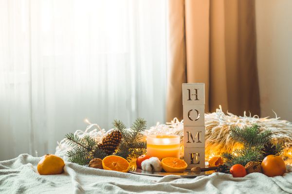 صبح دنج زمستان در خانه کلمه خانه و نارنگی در ترکیب زمستانی درختان کریسمس شمع ها مخروط ها پنبه بالش های گرم و گلدان های تزئینی روی زمینه نماد سال نو و کریسمس