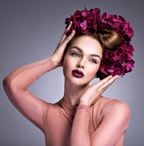 زن جوان با دسته گلهای بنفش در موهای خود دختری با مدل موهای خلاق و گل های شکوفه