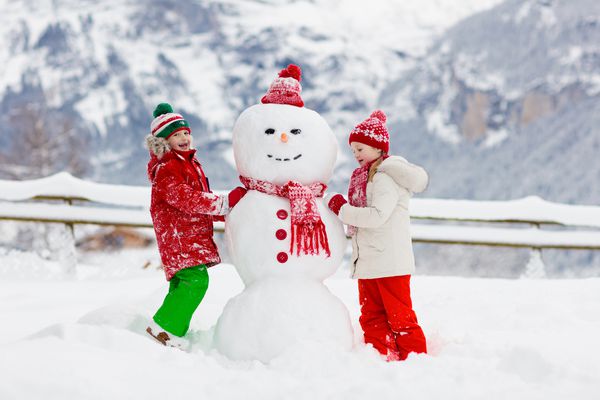 آدم برفی ساختمان کودک بچه ها آدم برفی می سازند پسر و دختر در بیرون از روز در زمستان برفی سرگرمی خانوادگی در فضای باز در تعطیلات کریسمس در کوه کودکان در منظره کوه سوئیس بازی می کنند