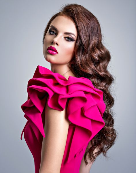 زن با پوشیدن لباس قرمز شیک و خلاق با مدل موهای خلاقانه پرتره دختر زیبا و شیک با موهای بلند مجعد زن جوان با چهره ای زیبا با رژ لب قرمز