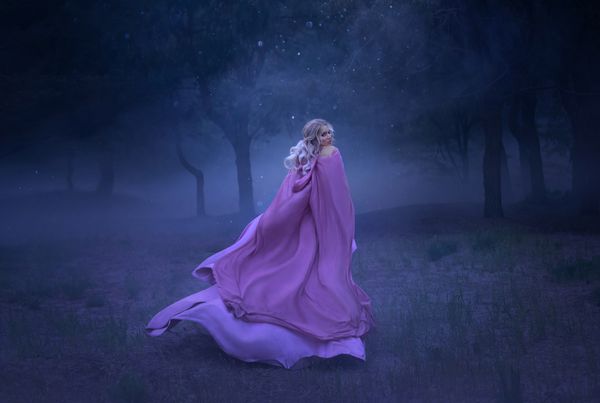 یک شاهزاده خانم جوان وروجک زرق و برق دار با موهایی که در یک جنگل پر از غبار سفید پوشیده با لباس بلند بنفش طولانی گران پرواز و در حال پرواز فرار می کند عکس یک زن زیبا در مهتاب