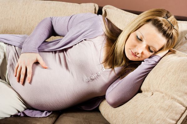 زن باردار در حال خوابیدن روی مبل است زمان چرت زدن