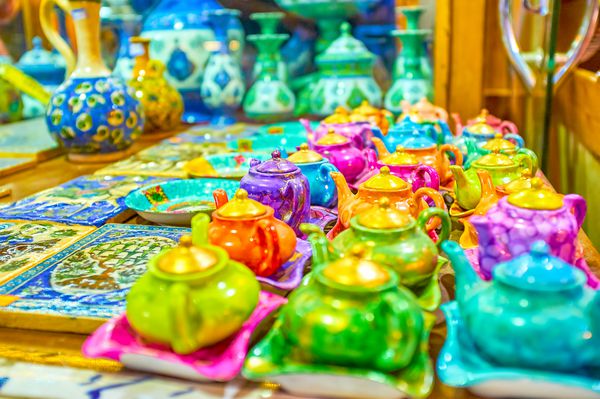 کتری های رنگی بشقاب و کاشی های رنگ شده در غرفه سفالگری در گرانداز بزرگ اصفهان ایران