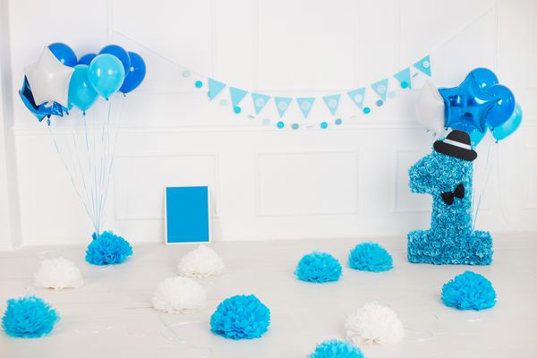 اتاق سفید که برای اولین جشن تولد پسر بچه با دکور آبی تزئین شده است عکس رنگی افقی