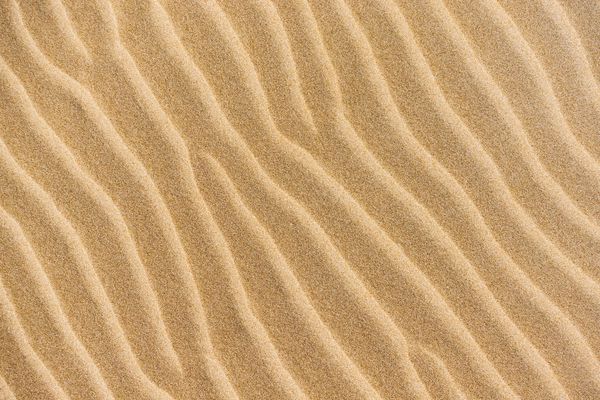 نمای بالای ساحل شنی و بافت ماسه قابل مشاهده الگوی پس زمینه با فضای کپی شن و ماسه زرد نزدیک در ساحل گرمسیری در زمان تابستان کویر طلایی در روز آفتابی زیبایی زمین