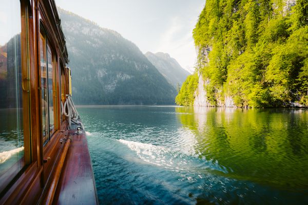 قایق مسافری سنتی که در یک روز آفتابی زیبا در تابستان در دریاچه کونیزسه با کوه واتزمن در حال گذر است Berchtesgadener Land Bavaria آلمان