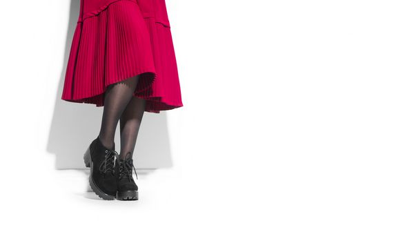 چکمه های زنانه کفش زیبا پاهای زن جوان در کفش های سیاه سوئد دامن و لباس دامن جدا شده بر روی زمینه سفید لباس زیبا