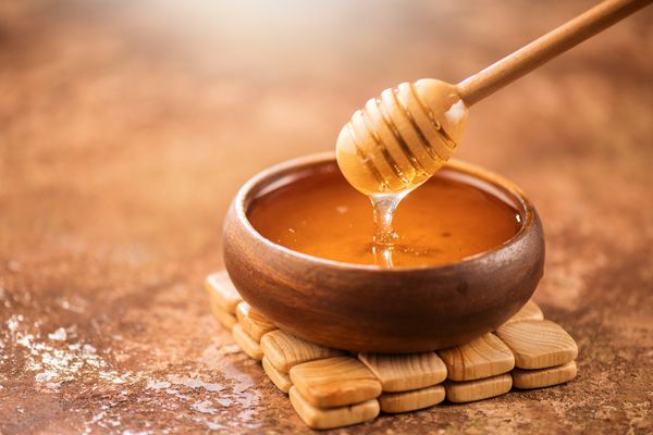عسل می ریزد از چنگال عسل در کاسه چوبی نزدیک سالم عسل ضخیم آلی ضخیم از قاشق چای عسل چوبی نزدیک