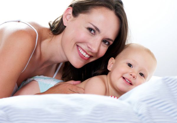 نزدیک عکس پرتره یک مادر و کودک که در رختخواب لبخند می زنند