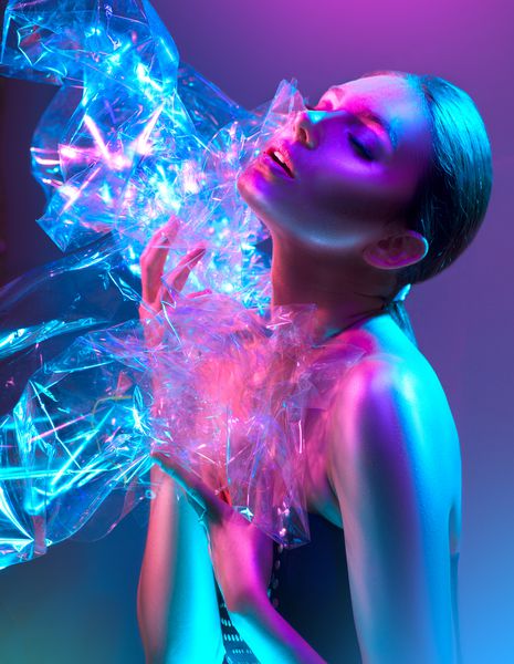 دختر مدل مد بالا در چراغ های نئون روشن و رنگارنگ که از طریق فیلم شفاف در استودیو قرار می گیرد پرتره زن زیبا در UV طراحی هنری رنگارنگ را تشکیل می دهند در پس زمینه رنگارنگ و واضح