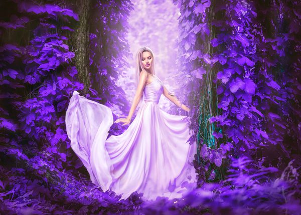 زن جوان رمانتیک زیبایی در لباس نوعی پارچه ابریشمی بلند با قرار دادن لباس در جنگل فانتزی در سرسبز بنفش دختر خوش تیپ عروس و لذت بخش از طبیعت در فضای باز لباس شلوغ باغ پاییزی