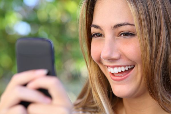 زن با اینترنت در تلفن هوشمند خود در فضای باز با پس زمینه روشن و تمرکز سبز در حال مرور است