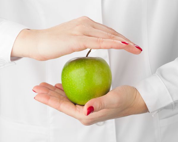سیب سبز در دست پس زمینه سفید