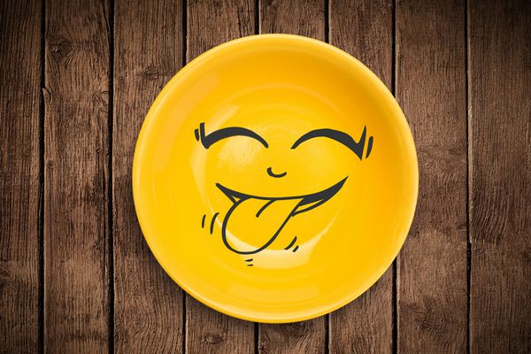 چهره کارتونی لبخند مبارک در صفحه بشقاب رنگارنگ و زمینه پس انداز