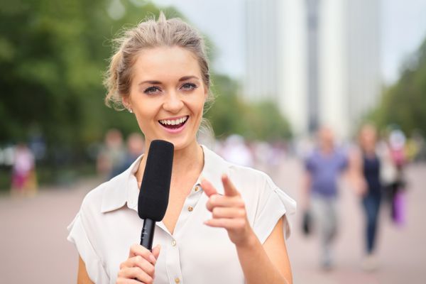 گزارشگر دختر خندان با میکروفون در خیابان