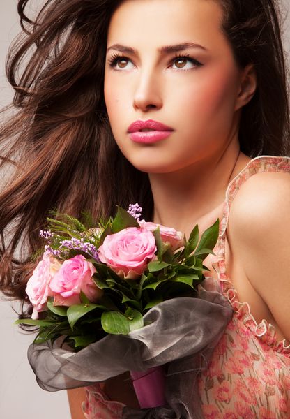 زن جوان زیبا که دارای یک دسته گل گل استودیویی است