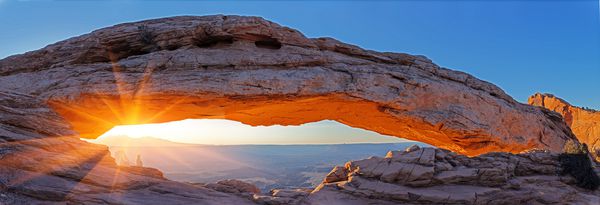 قوس طبیعی که در پرتوهای طلوع خورشید تابیده است Mesa Arch سرزمین های کانیون یوتا