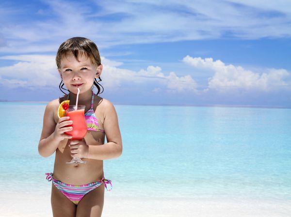 دختر کوچولو در ساحل در حال نوشیدن عجیب و غریب