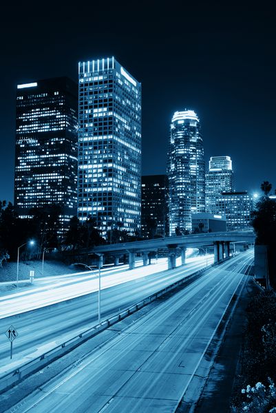 مرکز شهر لس آنجلس در شب با ساختمان های شهری و دنباله نور