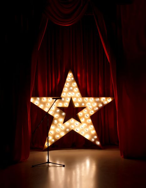 میکروفون روی صحنه تئاتر ستاره طلایی با پرده قرمز در اطراف