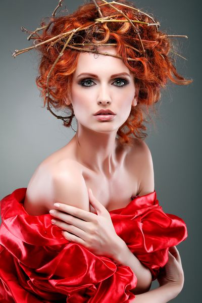 موهای قرمز پرتره دختر زیبا با پارچه قرمز در یک لوح از شاخه ها