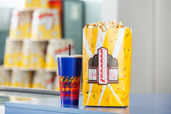 کیسه پاپ کورن و نوشیدنی سرد روی پیشخوان امتیاز در سینما