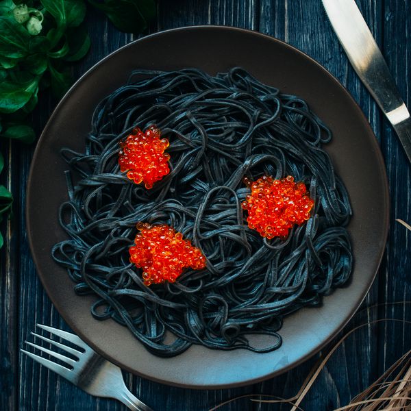 اسپاگتی سیاه با خاویار قرمز روی یک میز چوبی تیره