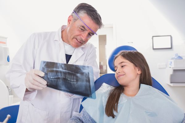 دندانپزشک کودکان در تشریح اشعه ایکس در کلینیک دندانپزشکی به بیمار جوان