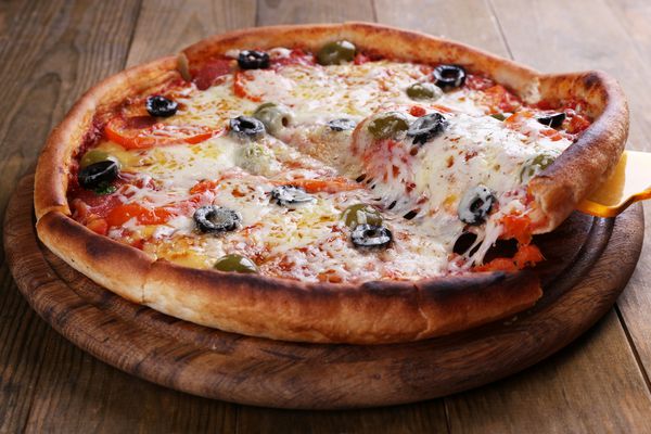 پیتزا با پنیر روی صفحه و زمینه چوبی میز
