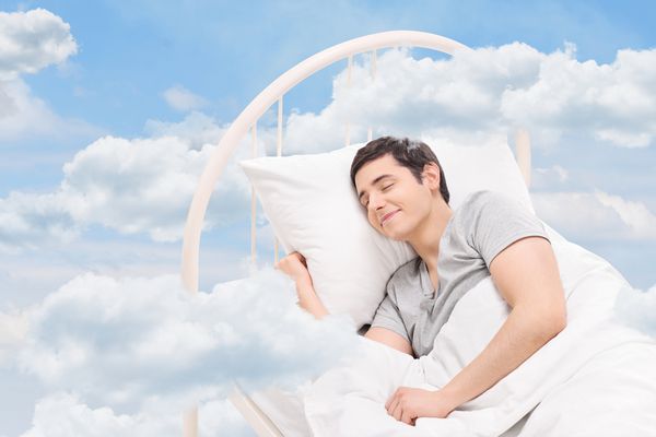 مردی شاد که روی تختی در ابرها خوابیده است
