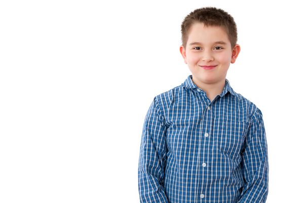 پرتره پسر بچه ناز 10 ساله با لبخند شیرین خوشگل در مقابل زمینه سفید و فضای کپی ایستاده است