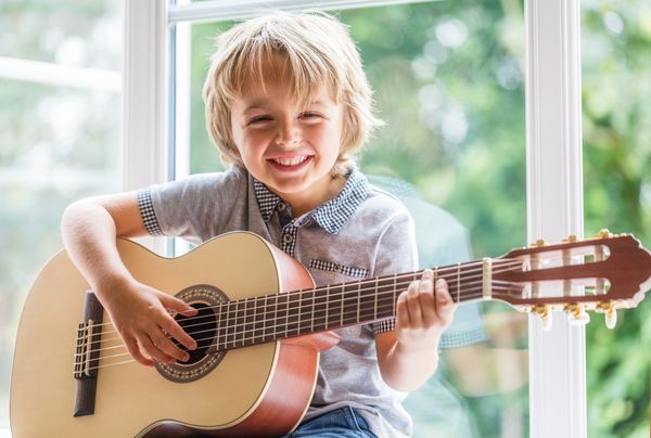 پسر خندان و یادگیری نواختن گیتار آکوستیک