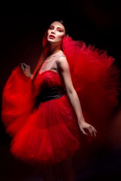 زن جوان شیک و زیبا با لباس قرمز بیش از پس زمینه سیاه نور مخلوط