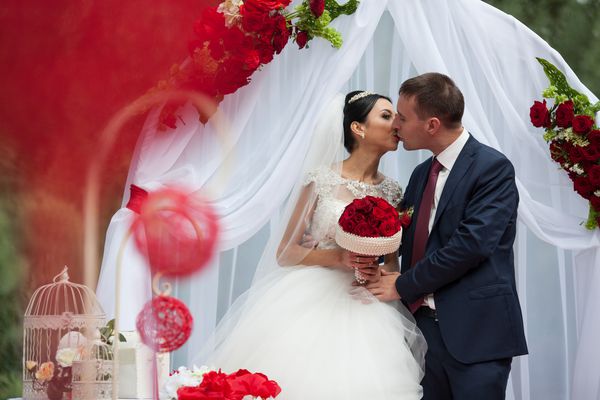زن و شوهر عاشقانه تازه متولد شده مبارک در راهرو عروسی با تزیینات قرمز و گل
