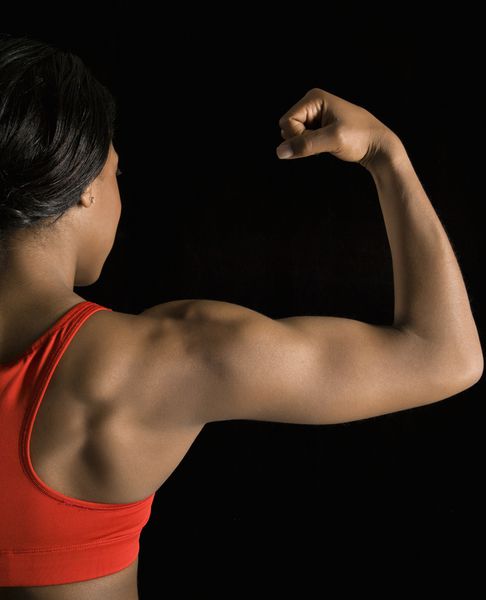 نمای عقب از زن آفریقایی آمریکایی که عضلات عضله را خم می کند