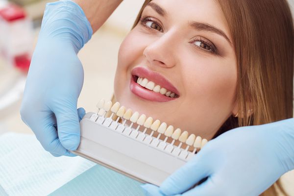 زن زیبا اروپایی با سفید کردن دندانهای سالم لبخند می زند مفهوم مراقبت از دندان ست کاشت با سایه های مختلف تن