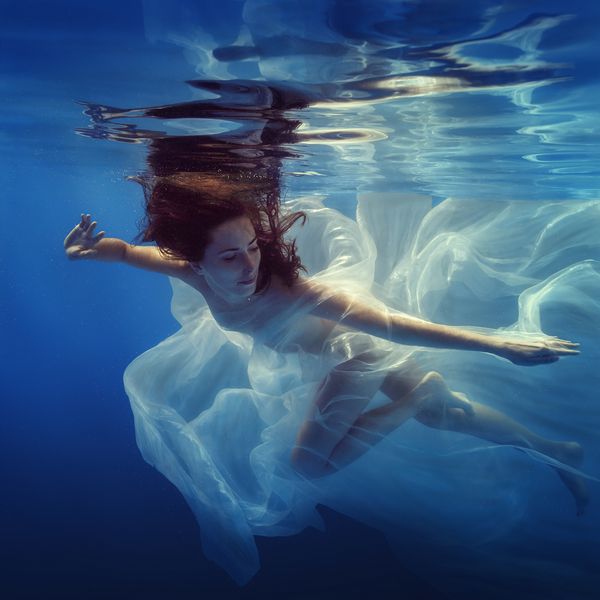 دختر با پارچه زیر آب شنا می کند