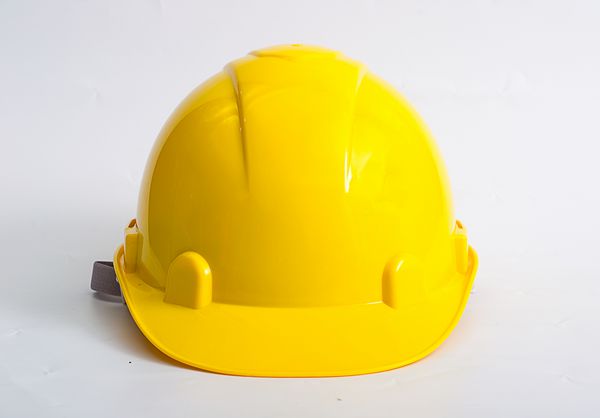 بسته شدن کلاه محافظ زرد بر روی زمینه سفید مفهوم امنیت و محافظت در محل کار