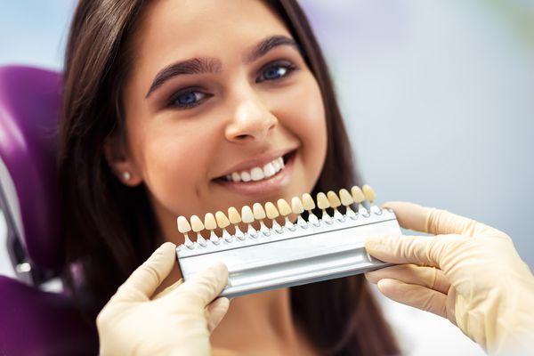 زن زیبا اروپایی با سفید کردن دندانهای سالم لبخند می زند مفهوم مراقبت از دندان ست کاشت با سایه های مختلف تن