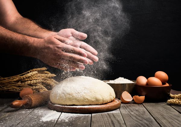 نانوایی در حال پختن نان آرد را روی خمیر سیلی می زند مرد نان درست می کند