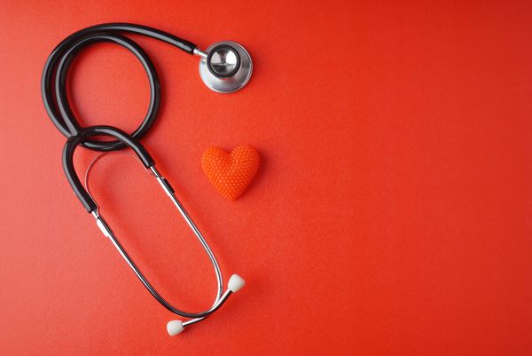 استتوسکوپ با قلب بر روی زمینه قرمز و فضا برای متن مفهوم سلامتی مفهوم پزشکی