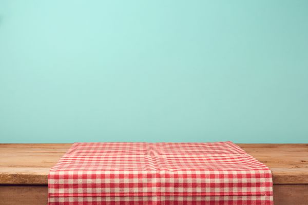 میز عرشه چوبی خالی و رومیزی قرمز رنگ بر روی زمینه کاغذ دیواری نعنا