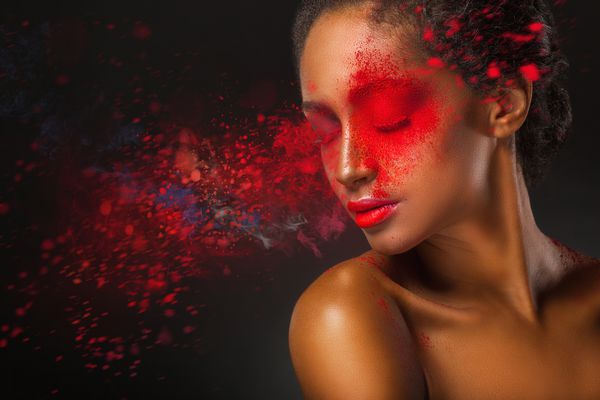 آرایش مد صورت نزدیک یک زن جوان زیبا با پاشیدن رنگ قرمز بر روی زمینه سیاه