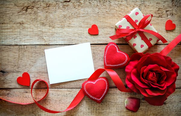 قلب های قرمز گل رز روبان کارت پیام و جعبه هدیه روی میز چوبی زمینه روز ولنتاین