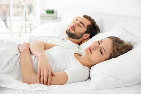 زن و شوهر ناز جوان که با هم در رختخواب می خوابند