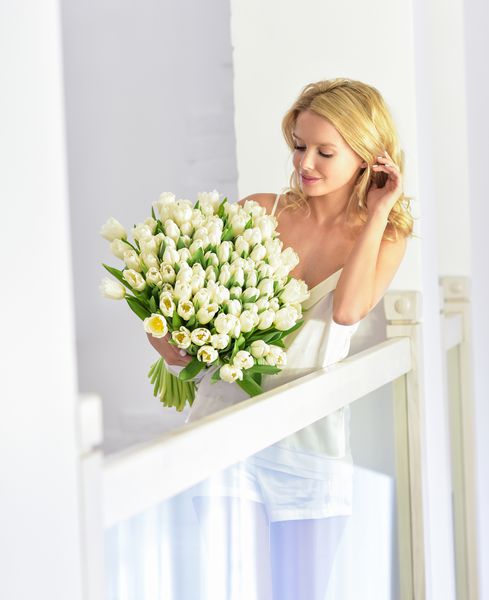 زن جوان زیبا با دسته گل لاله پرتره بهار در خانه داخلی بهار